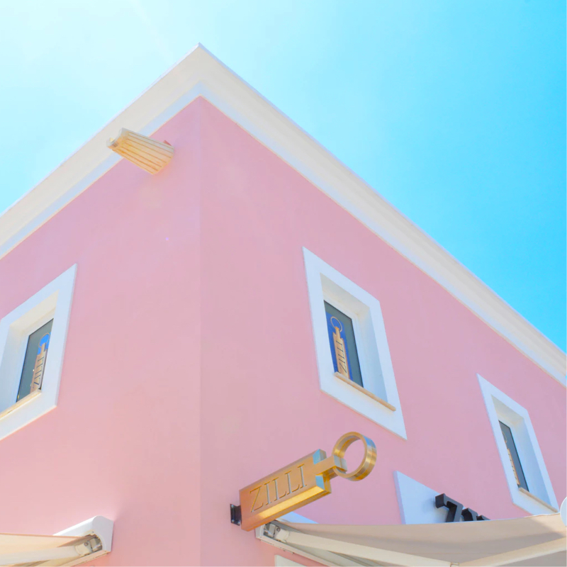 looking up at a bubblegum pink building against a clear blue sky